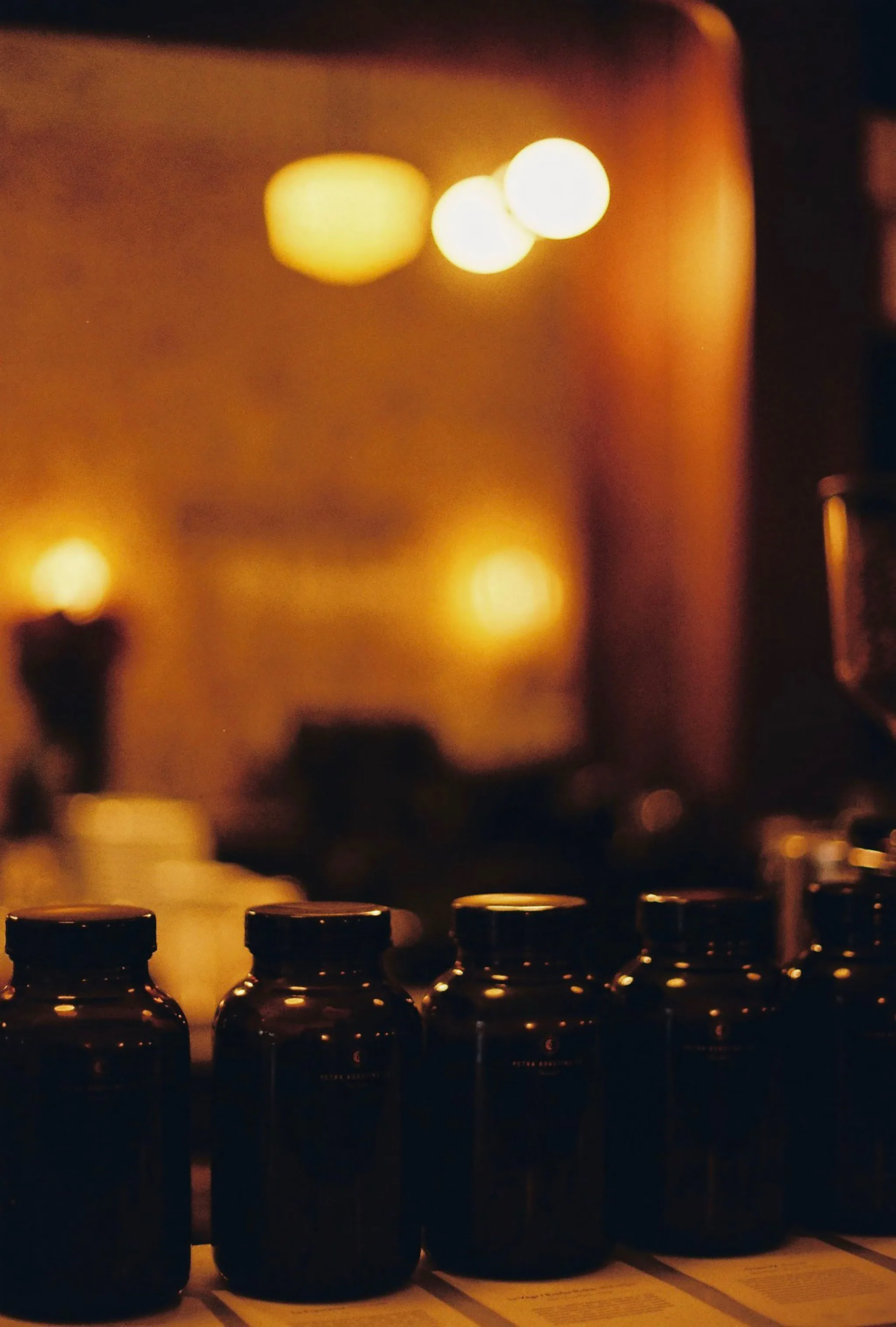 A row of amber apothecary jars in front of warm out-of-focus candle light